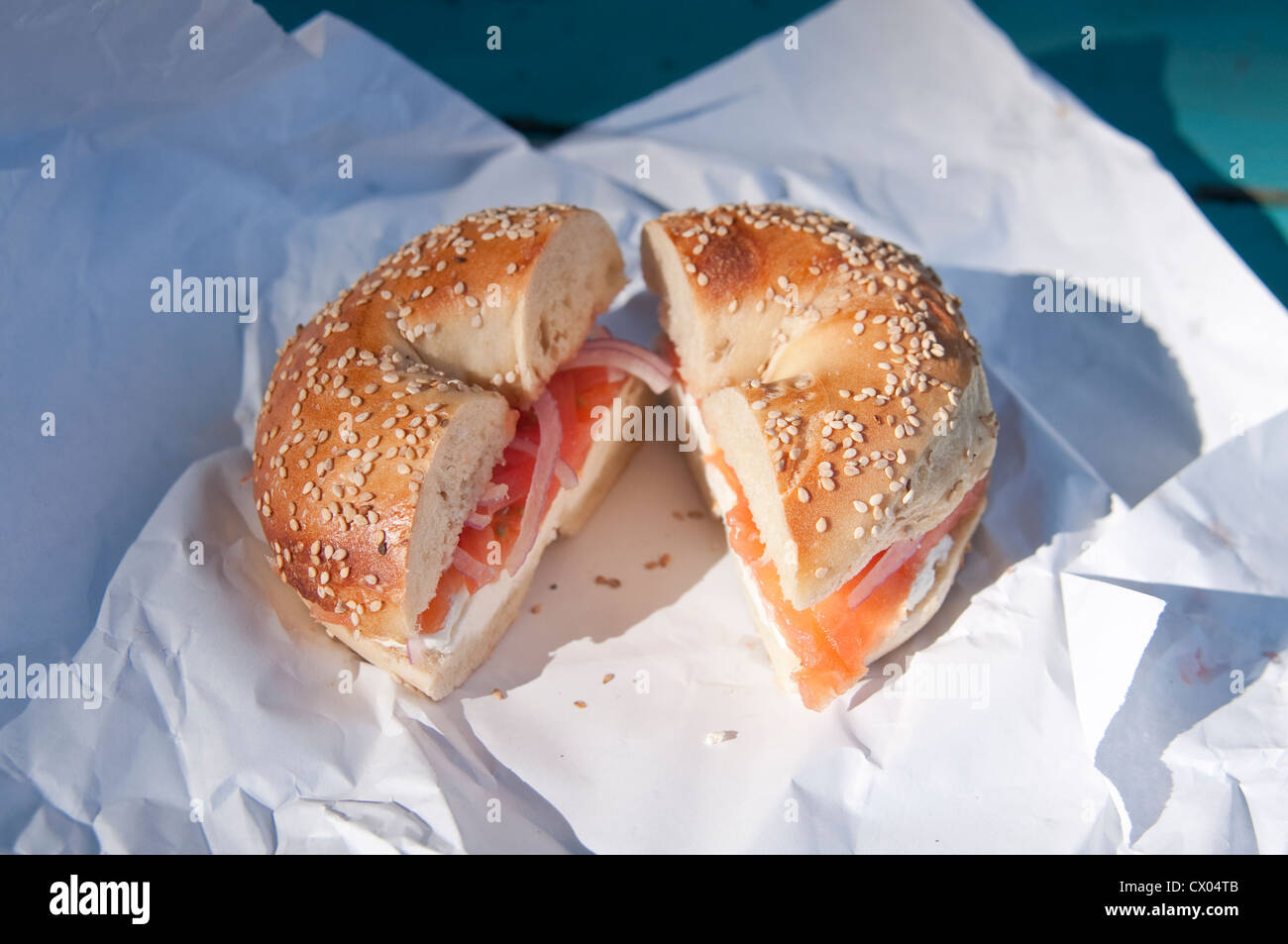 Un seme di sesamo bagel con lox (salmone affumicato), la crema di formaggio, cipolla e pomodoro, seduto su un involucro di carta, dalla struttura a molla bagel in Englewood, NJ. Foto Stock