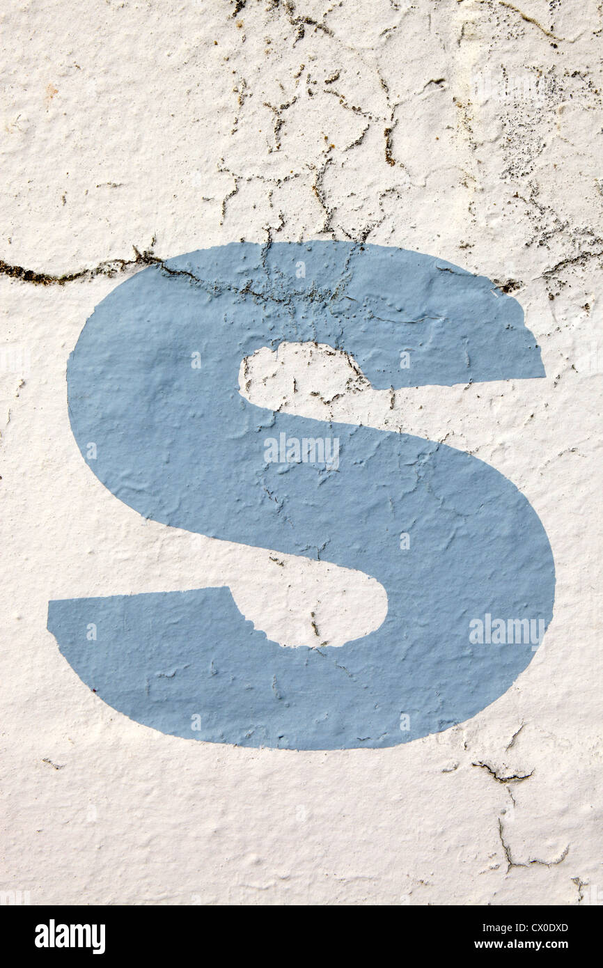 Blu cielo lettera 'S' stampata sulla sbriciolamento muro bianco, Cornwall, Regno Unito Foto Stock