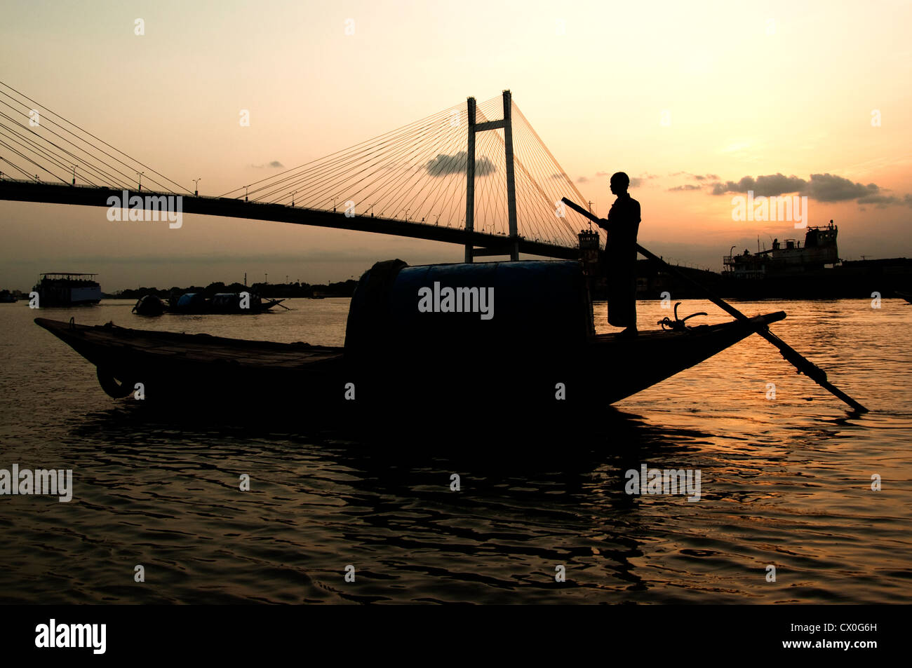 Un boatman che si alza sulla sua barca la sera sopra il fiume Ganges a Kolkata, Indai. Foto Stock