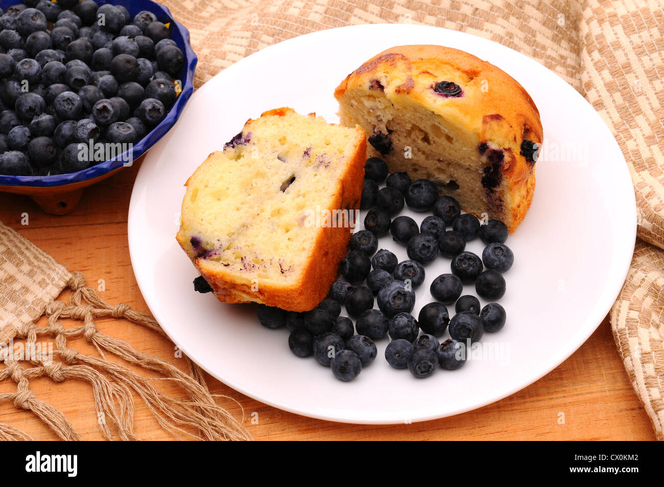 Deliziosi muffin ai mirtilli tagliato a metà con bacche allentato su una piastra bianca su una tavola in legno rustico. Foto Stock