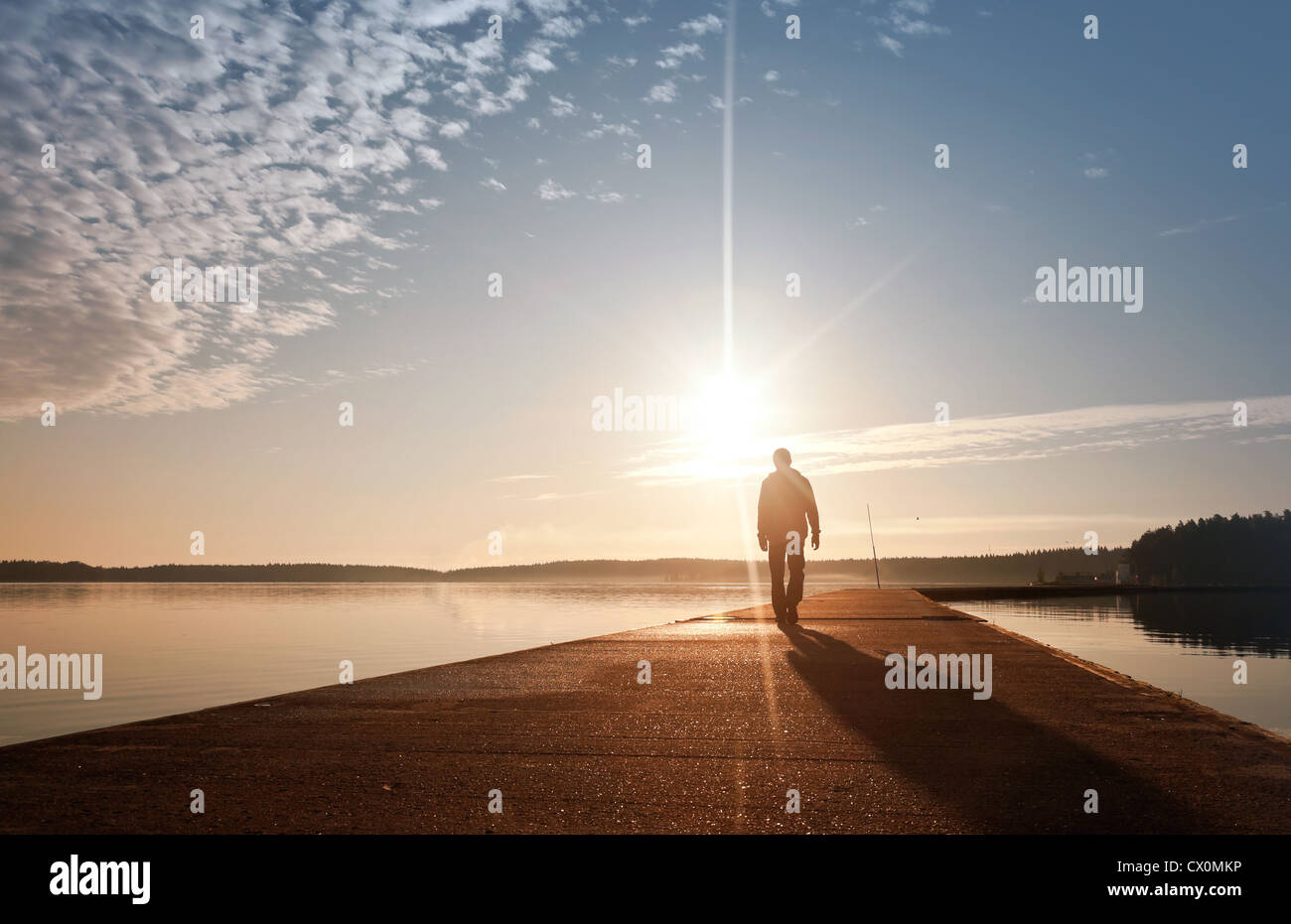 Un uomo passa sul molo di cemento in presenza di luce solare Foto Stock