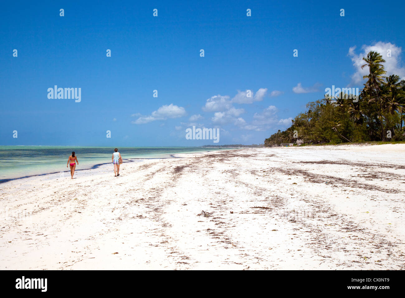 La gente che camminava su una spiaggia deserta di sabbia bianca, Bwejuu, Zanzibar africa Foto Stock