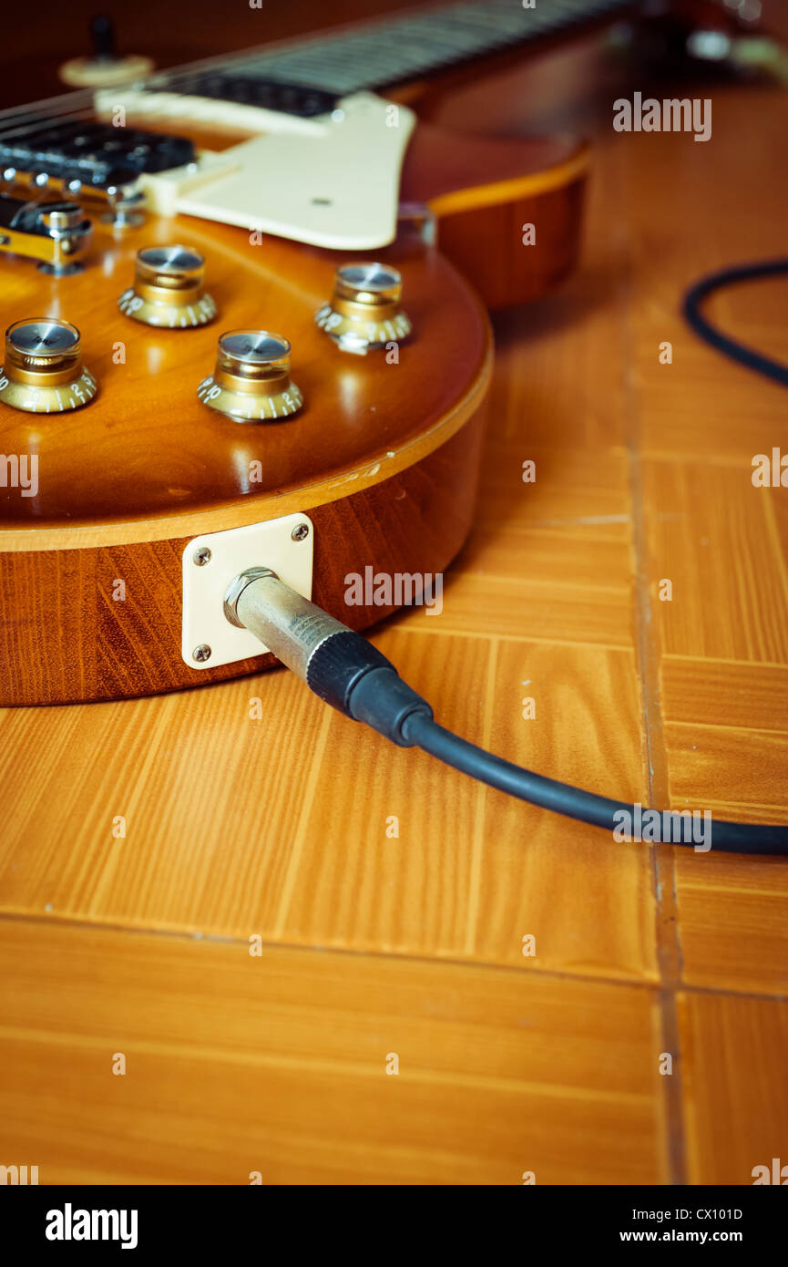 Chitarra elettrica miele burst colore sul pavimento con cavo jack Foto Stock