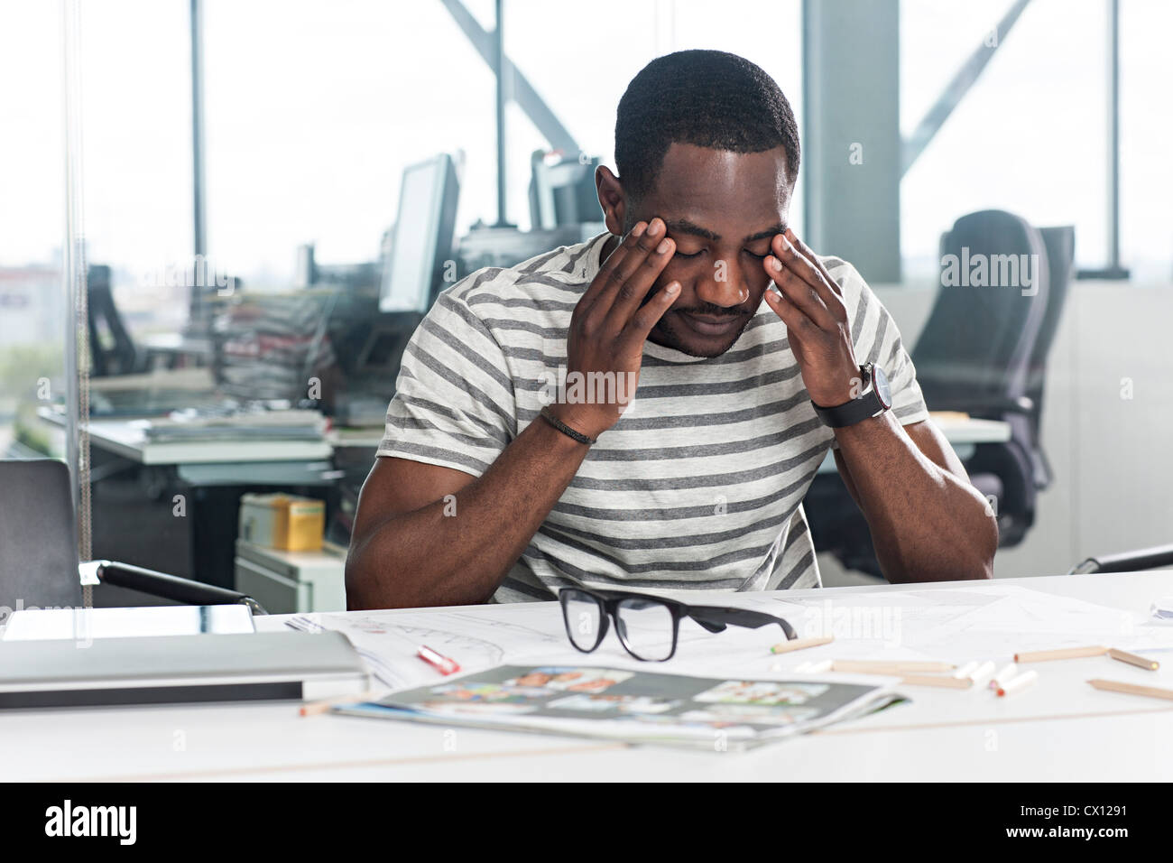 Preoccupato cerca uomo con piani sulla scrivania Foto Stock