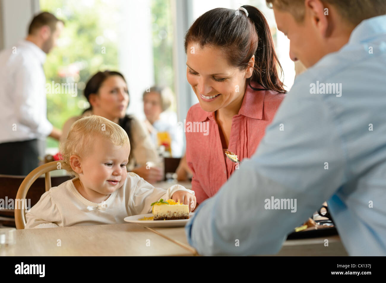 Il padre e la madre con bambino di mangiare la torta donna uomo cafe Foto Stock