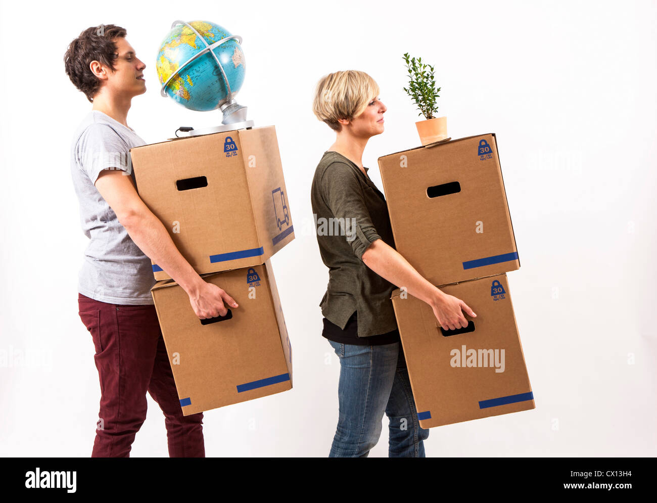 Symbolfoto Umzug, Auszug, umziehen. Junges Paar trägt Umzugskartons, Zimmerpflanze und Globus. Umzugskisten Pappkarton aus. Foto Stock