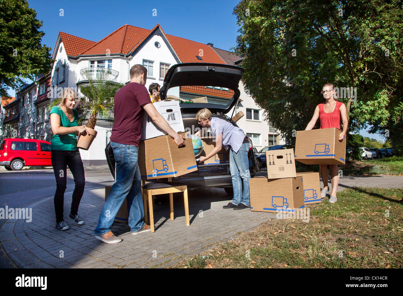 In movimento. I giovani che si spostano da uno a casa in uno nuovo. Che trasportano contenitori per il trasloco , mobili, le cose in un auto privata. Foto Stock