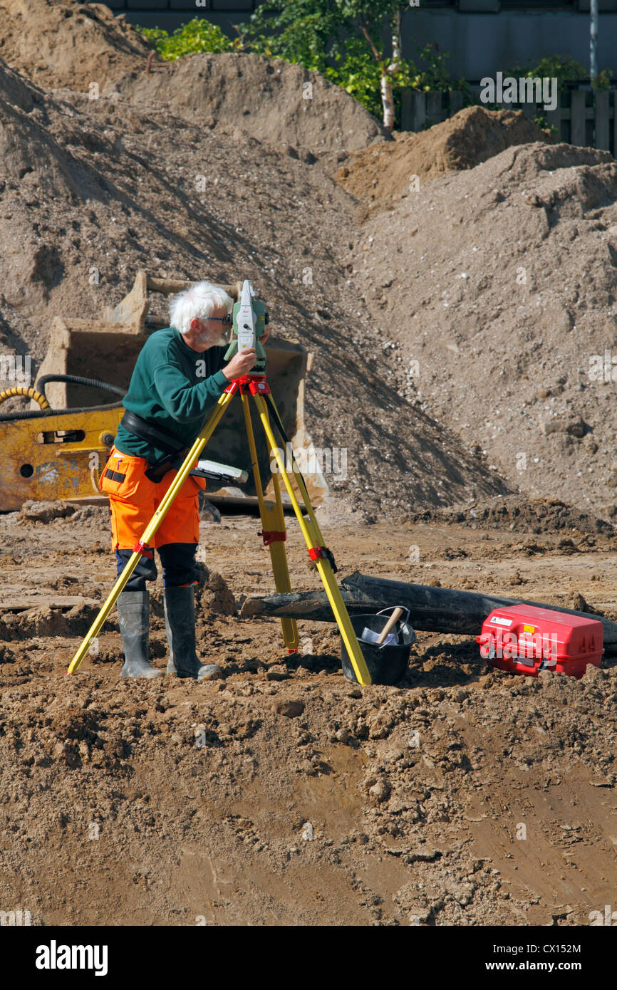 Surveyor e la sua Leica stazione totale la mappatura di un sito in costruzione prima della costruzione di un nuovo supermercato di Hørsholm, Danimarca. Foto Stock