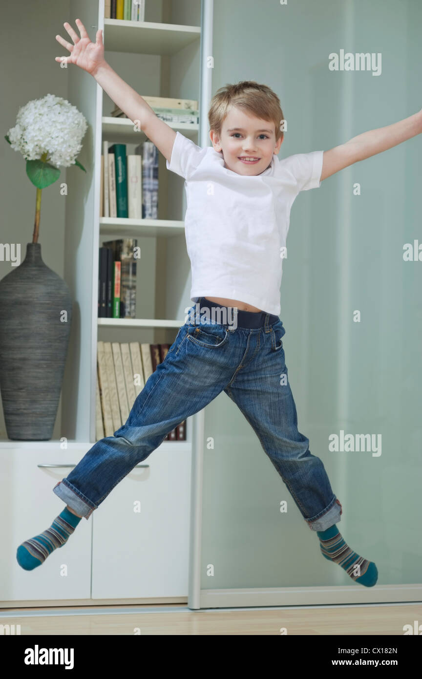 Ritratto di un ragazzo in casuals jumping in mid-aria di casa Foto Stock