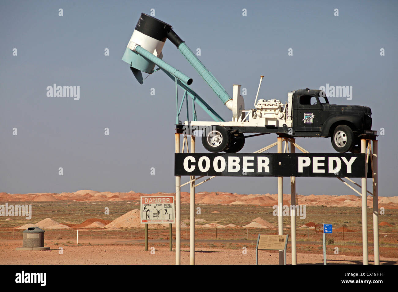 Segno della città con un tipico veicolo di data mining nel paesaggio intorno a Coober Pedy, South Australia, Australia Foto Stock