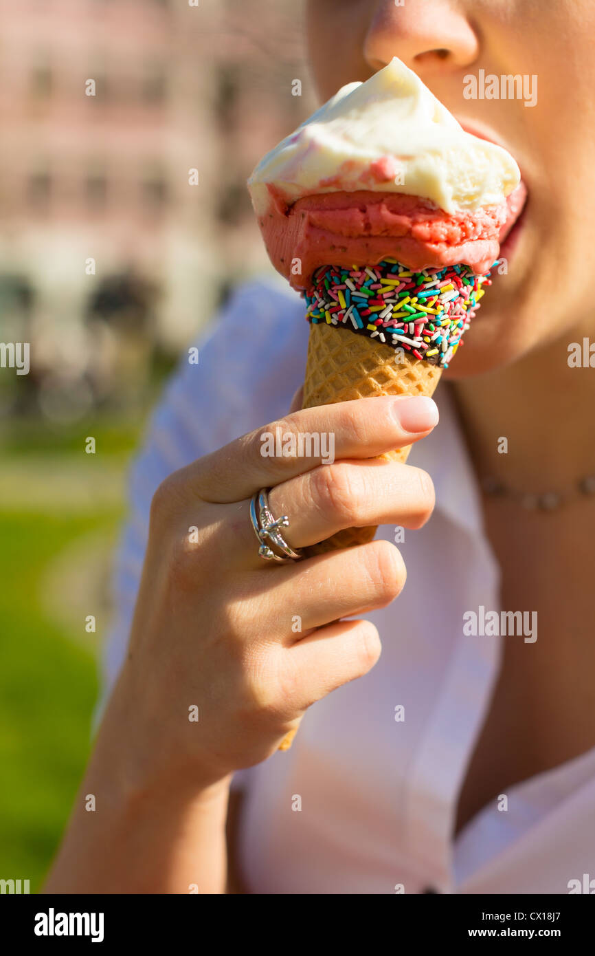 Giovane donna mangia il cono gelato in un parco Foto Stock