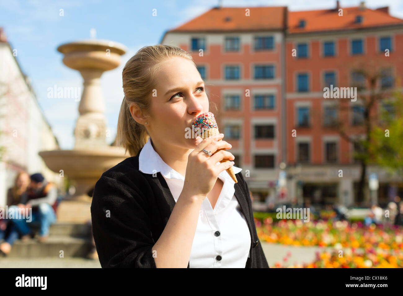 Giovane donna mangia il cono gelato in un parco Foto Stock
