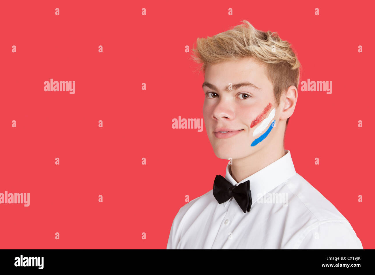 Ritratto di un giovane uomo con bandiera olandese sul suo volto su sfondo rosso Foto Stock