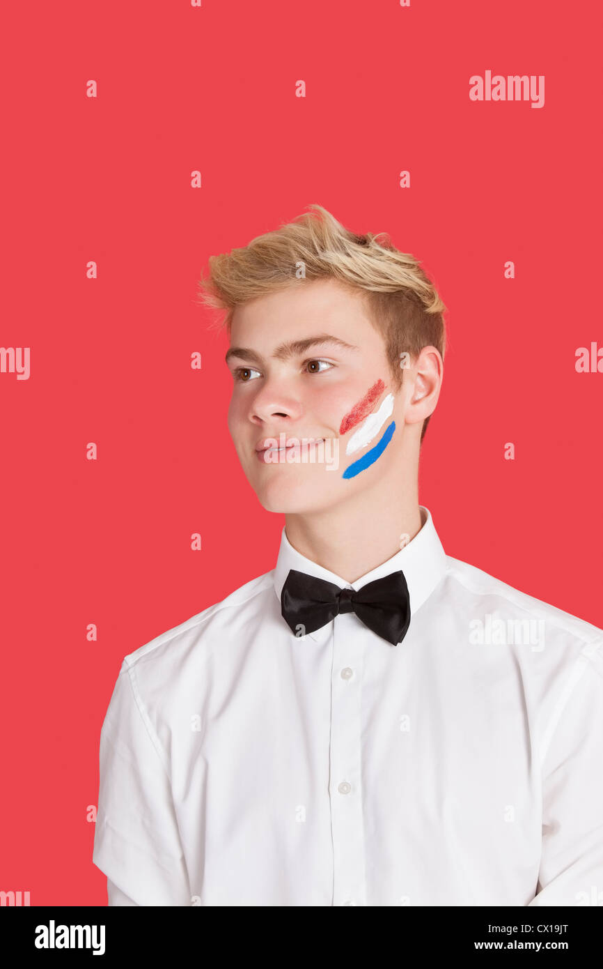 Felice giovane con bandiera olandese dipinto sul suo volto su sfondo rosso Foto Stock