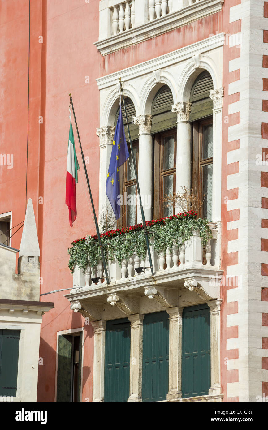 Frammento della facciata di un edificio antico con un balcone, ornamenti e bandiere Foto Stock