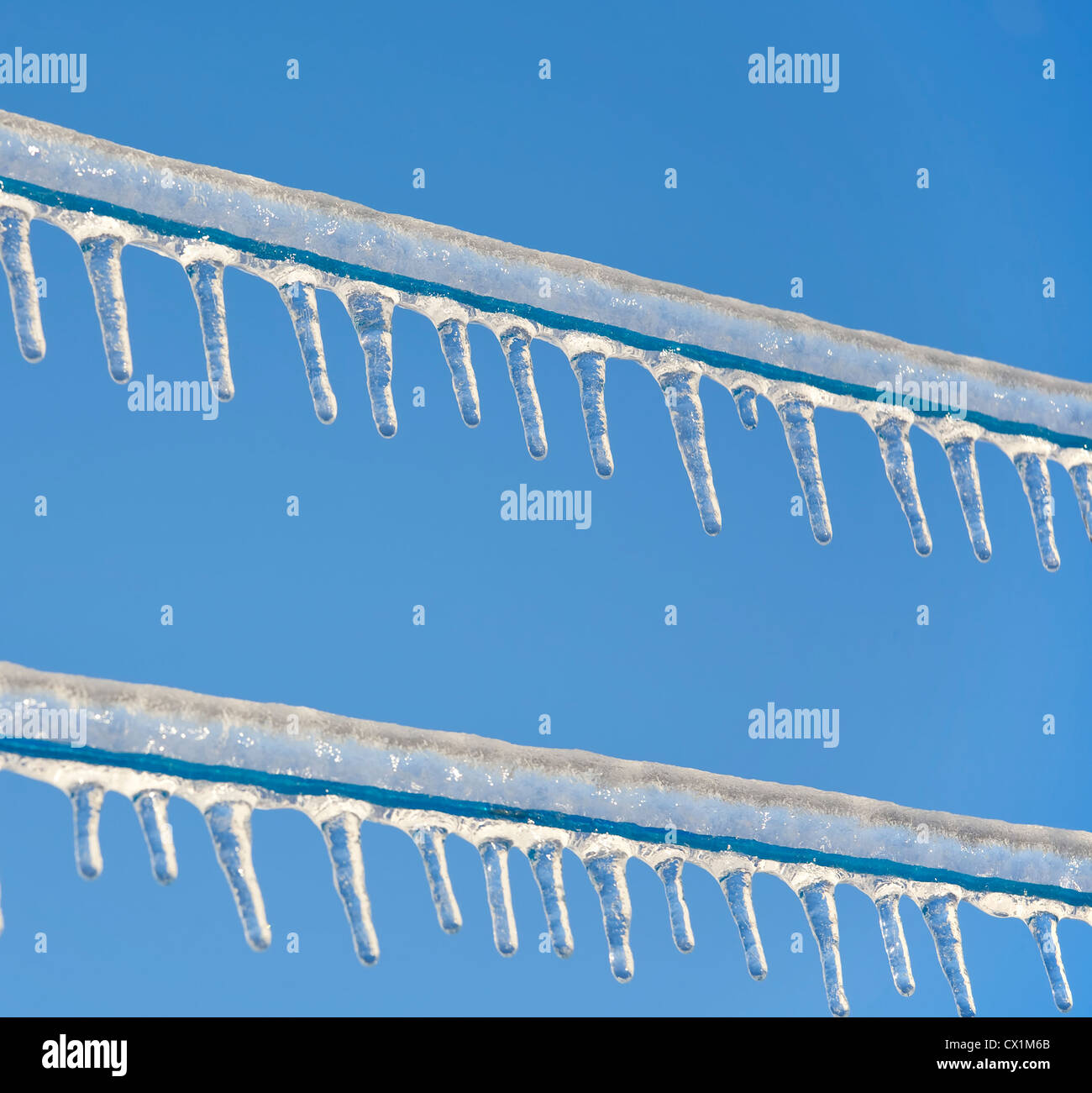 Ghiaccioli appesi da un congelati stendibiancheria contro un luminoso cielo blu chiaro. Foto Stock