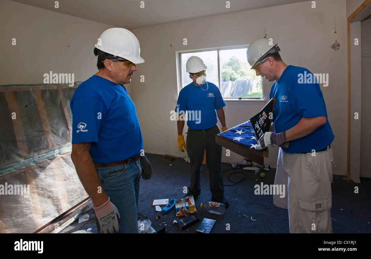 Volontari ristrutturando una casa per Habitat for Humanity scoprire bandiera militare e medaglie a sinistra dietro dopo la preclusione. Foto Stock