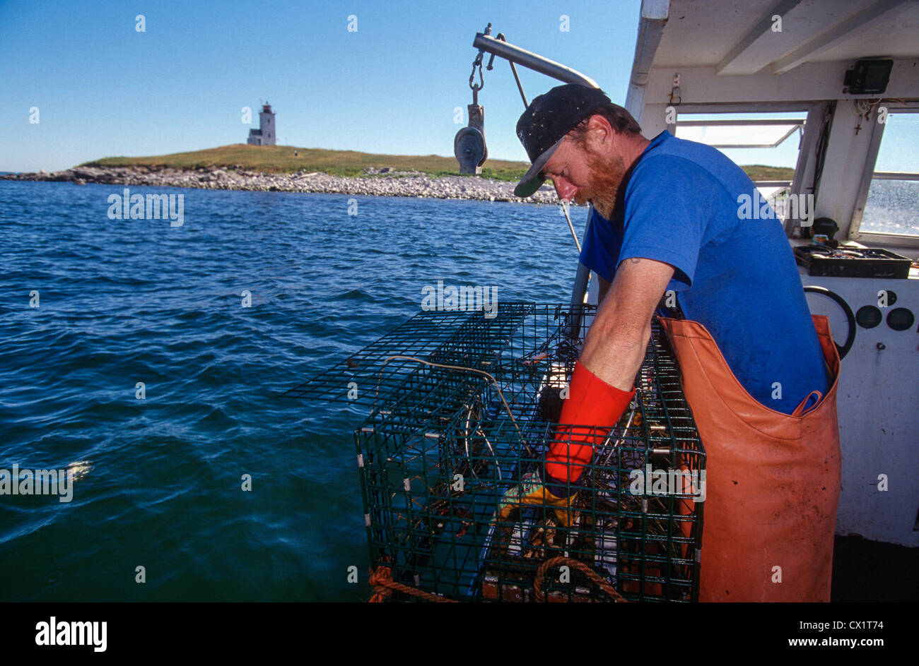 Lobster fisherman cale sue trappole con Matinicus Rock Stazione di luce sullo sfondo lungo la metà costa del Maine. Foto Stock