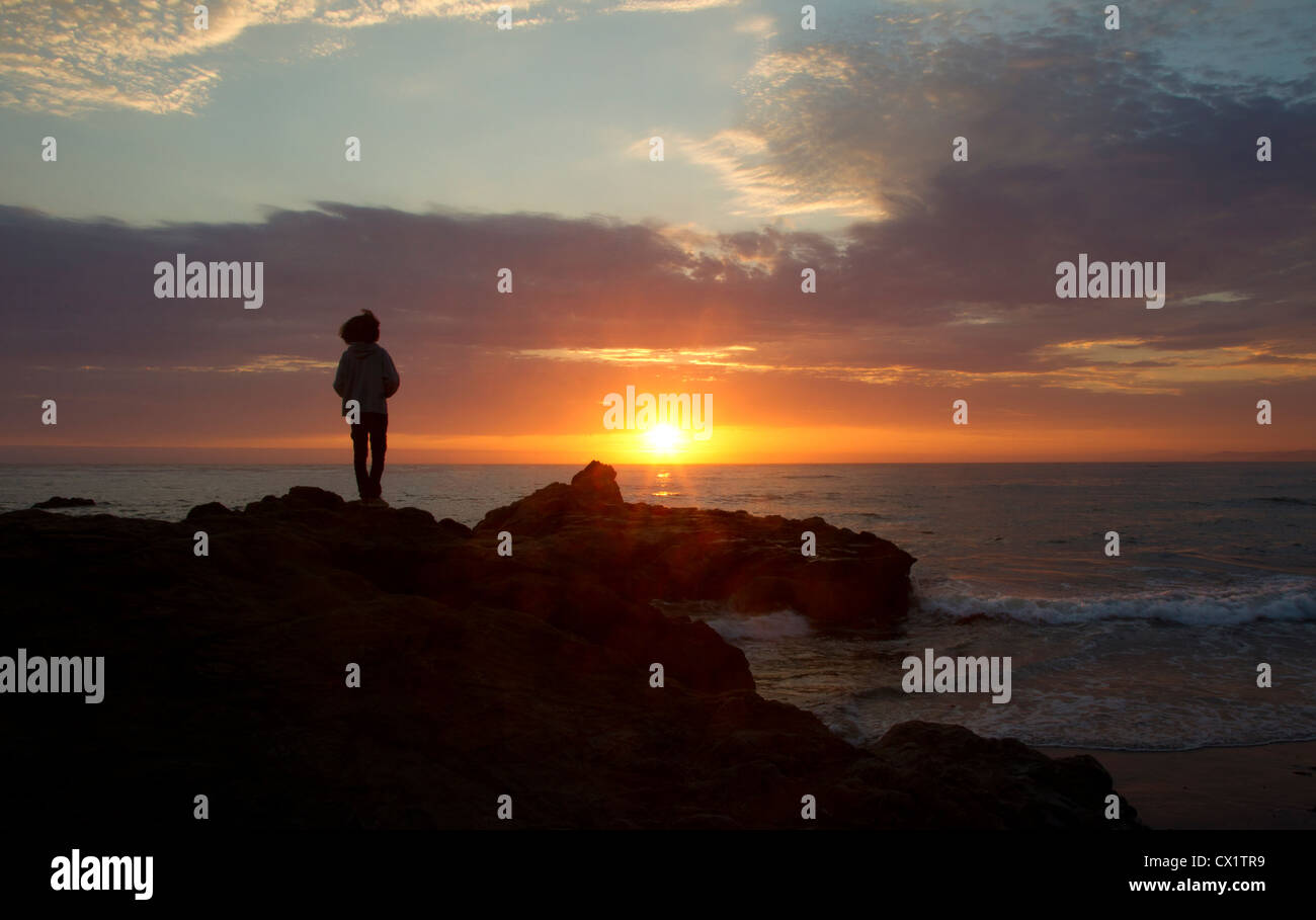 Persona che guarda il tramonto sull'Oceano Pacifico Foto Stock