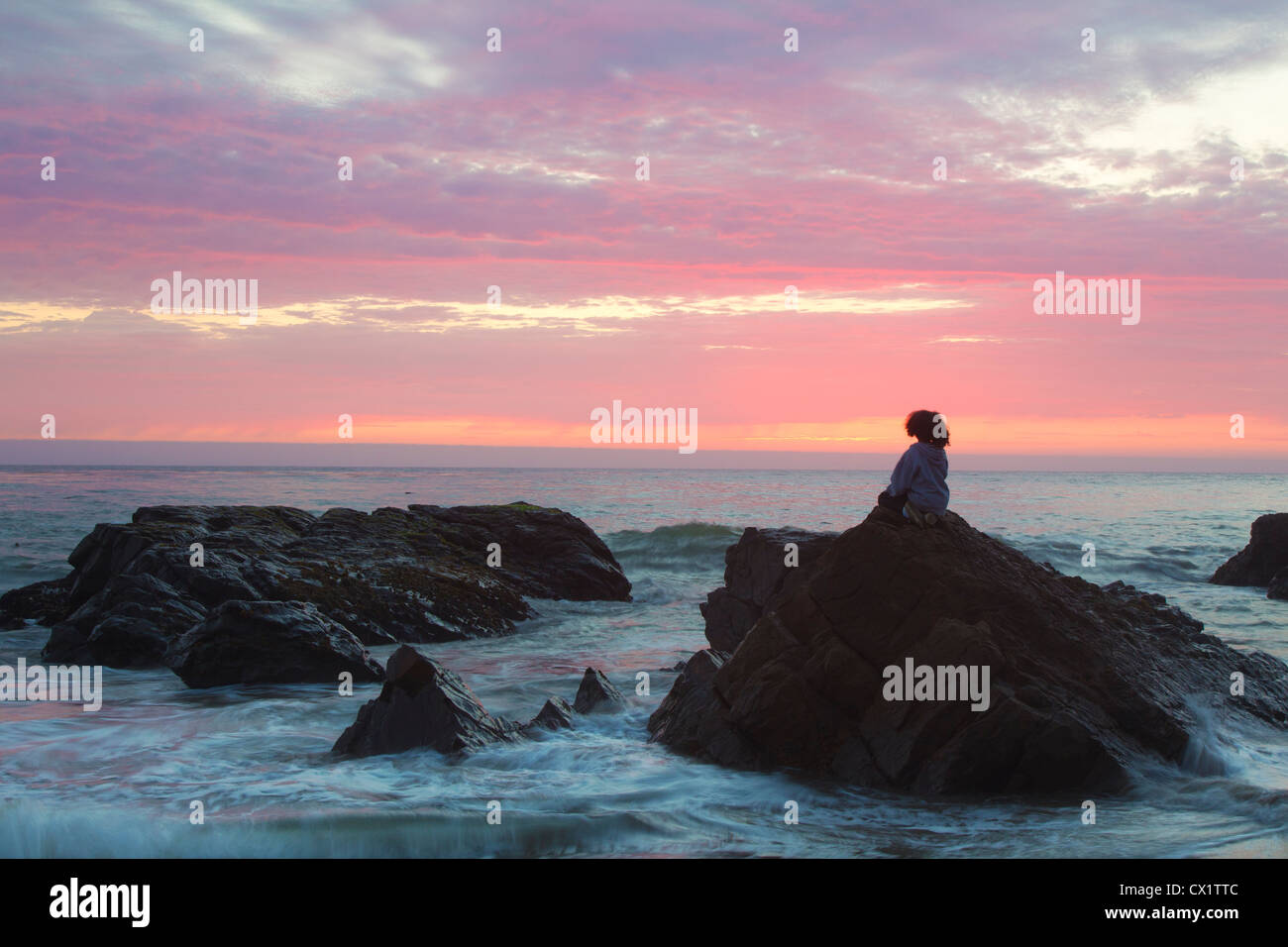 Persona che guarda il tramonto sull'Oceano Pacifico Foto Stock