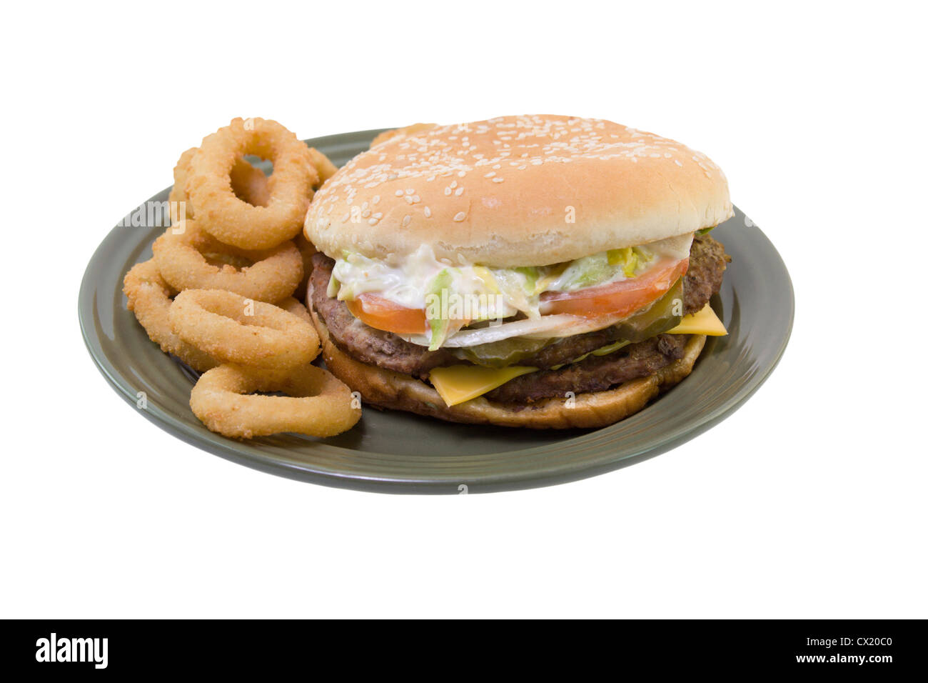 Double stack cheeseburger con pomodori, lattuga, cipolla, mayo, sottaceti e anelli di cipolla su una piastra verde isolato su bianco Foto Stock