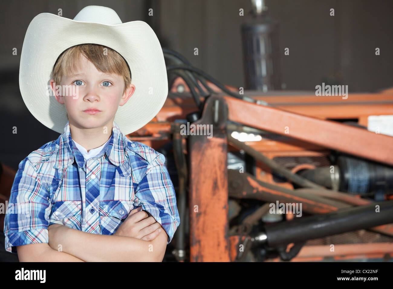 Ritratto di un ragazzo che indossa il cappello da cowboy mentre in piedi con le braccia incrociate contro la macchina Foto Stock