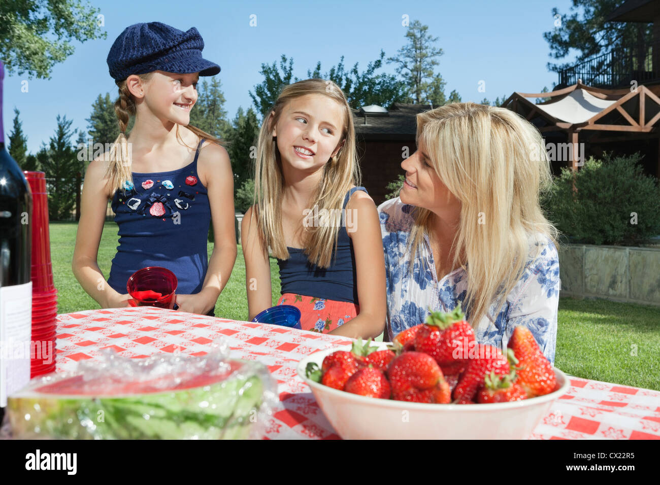 Madre comunicando con le figlie mentre è seduto alla outdoor tavolo da pranzo Foto Stock