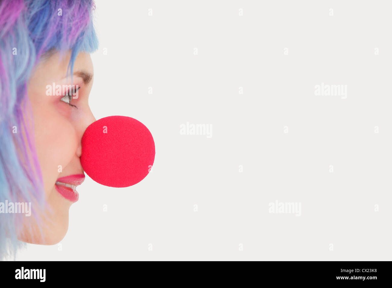 Profilo di donna con red clown naso su sfondo grigio Foto Stock