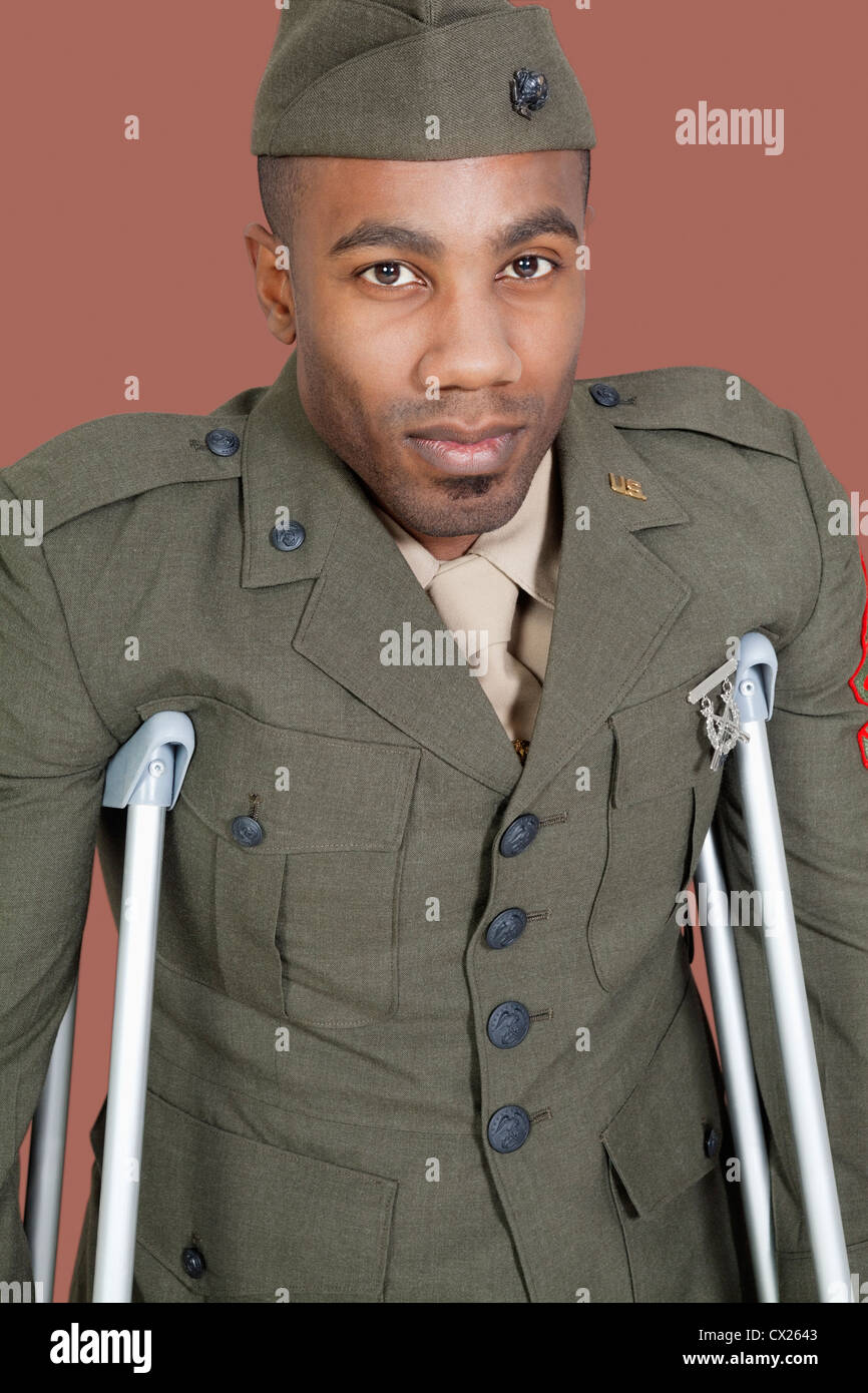 Ritratto di un afro-americano US ufficiale militare con le stampelle su sfondo marrone Foto Stock