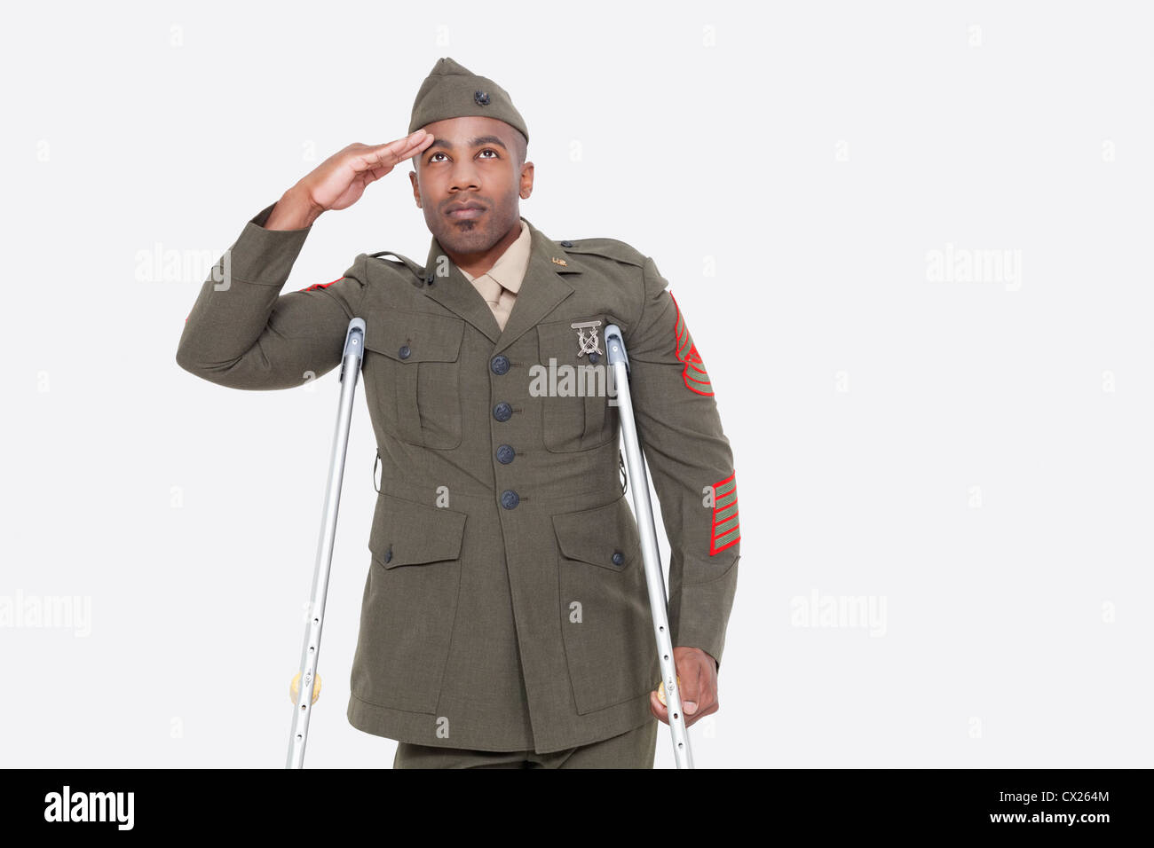 Disabilitato African American ufficiale militare in uniforme saluta su sfondo grigio Foto Stock