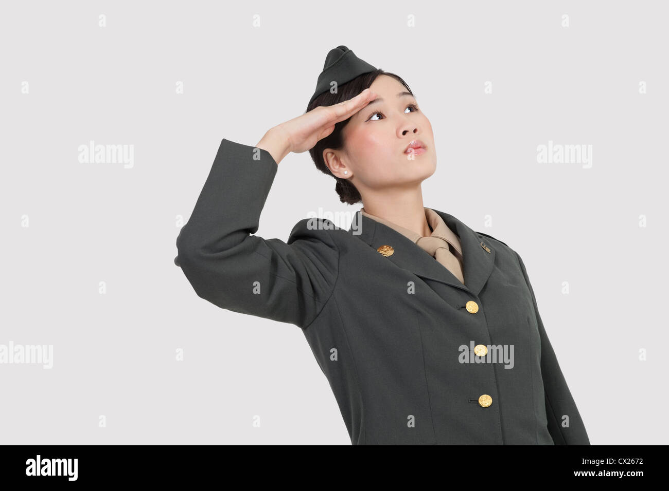 Grave ci femmina ufficiale militare salutando su sfondo grigio Foto Stock