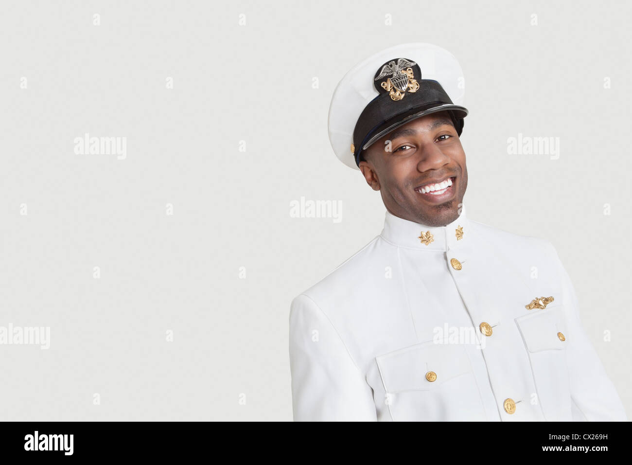 Ritratto di un giovane americano africano US Navy officer sorridente su sfondo grigio Foto Stock