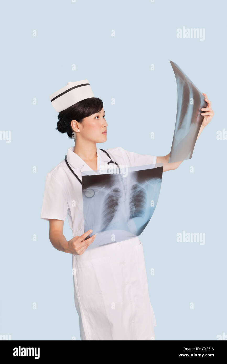 Medico donna analisi di raggi x reports su fondo azzurro Foto Stock