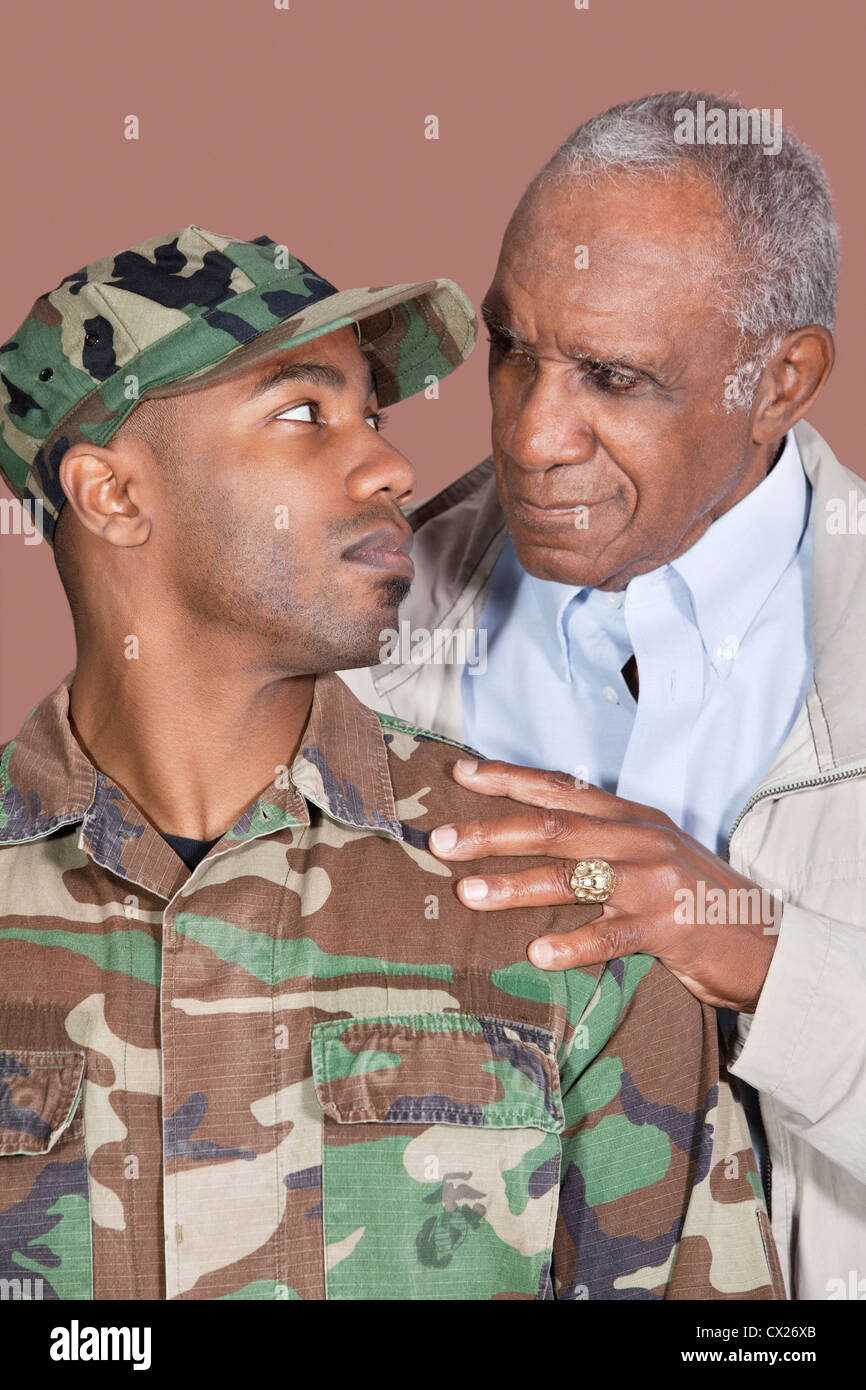 Padre e US Marine Corps soldato guardando ogni altro su sfondo marrone Foto Stock