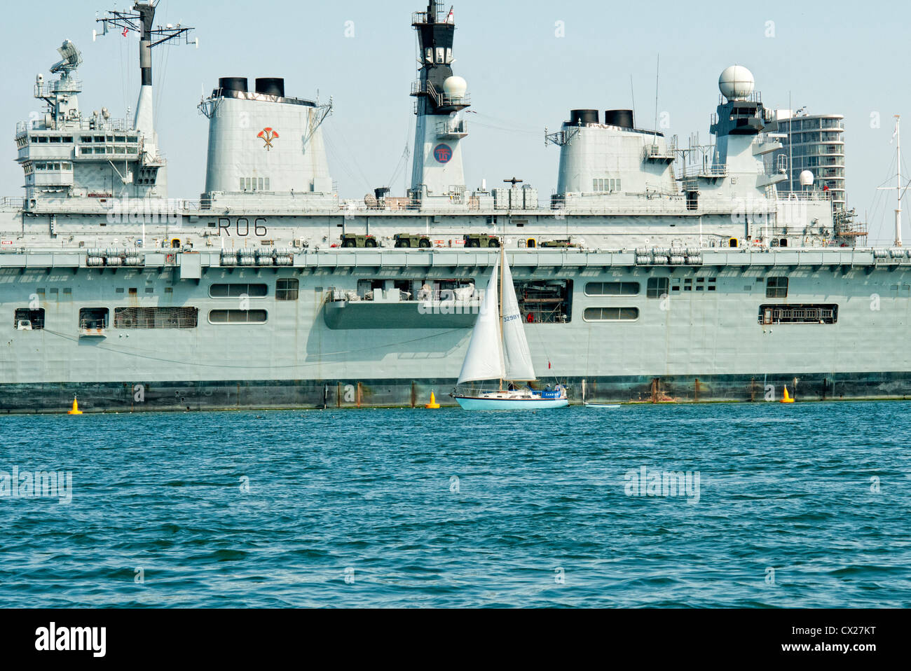 Sailing yacht andando passato illustre HMS ( R06 ) nel porto di Portsmouth Foto Stock