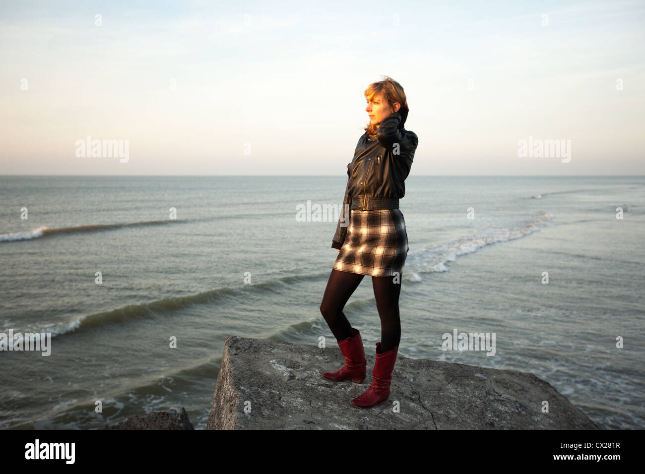 Ragazza bionda e guardare il tramonto vicino al mare Foto Stock