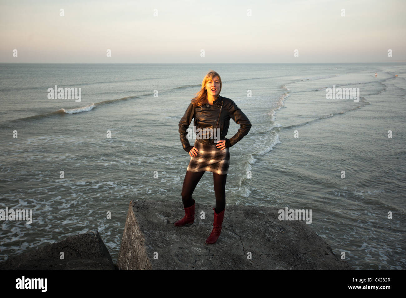 Ragazza bionda flirtare al tramonto vicino al mare Foto Stock