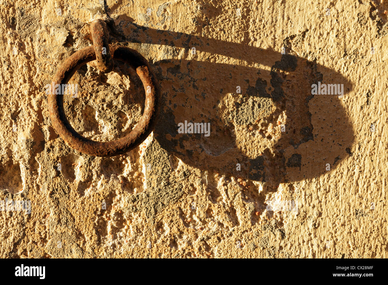 Vecchio arrugginito anello di ormeggio sul muro di pietra al tramonto con ombre lunghe Foto Stock