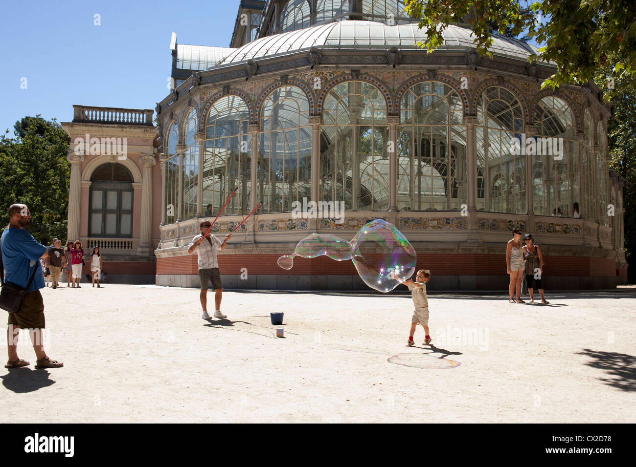 Un ragazzo cerca per far scoppiare una bolla di sapone al di fuori del Palacio de Cristal nel Parco del Retiro di Madrid, Spagna. Foto Stock