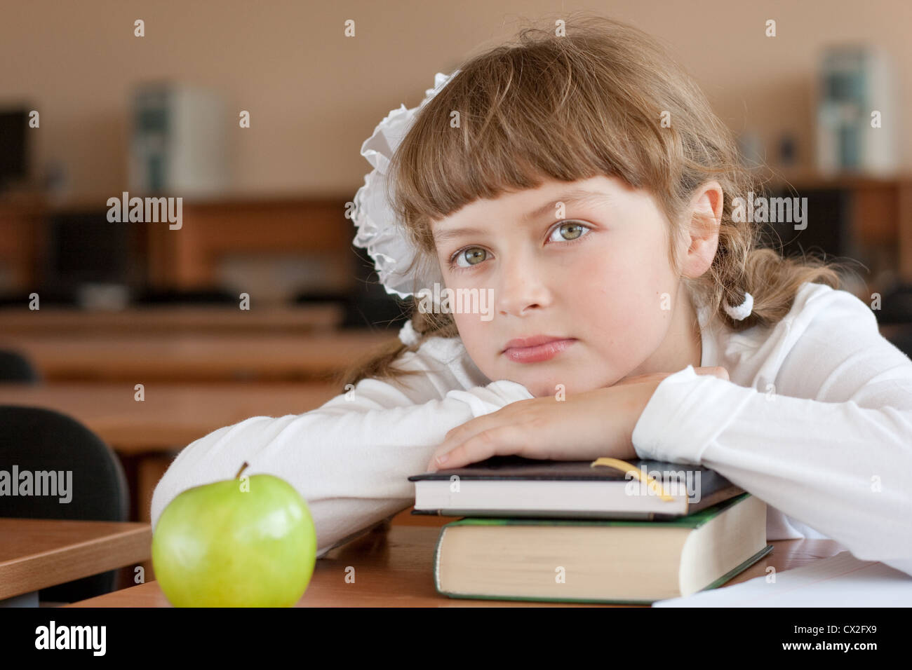 Schoolgirl il ritratto al banco di scuola con i suoi libri Foto Stock