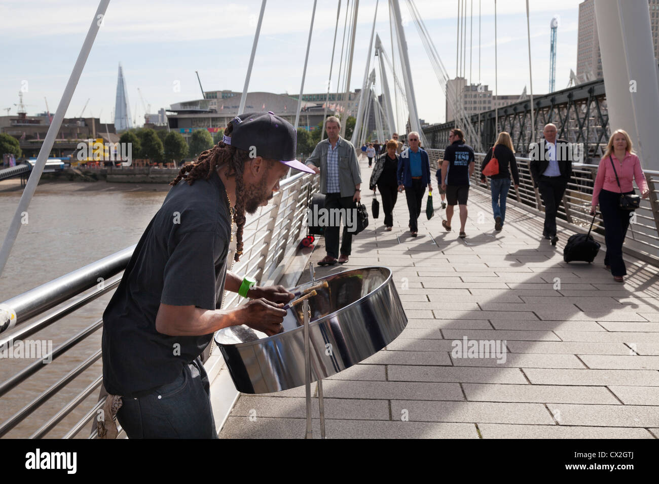 Busker riproduzione di nastro di acciaio tamburo (steelpan) sul Giubileo d oro ponte pedonale sul Tamigi da Hungerford Bridge. Foto Stock