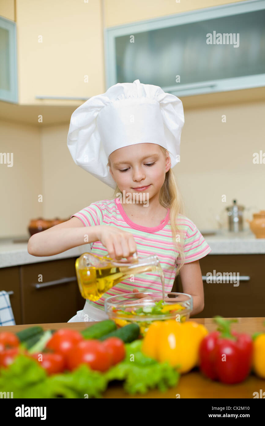 Bambina con olio la preparazione di un alimento sano su cucina Foto Stock