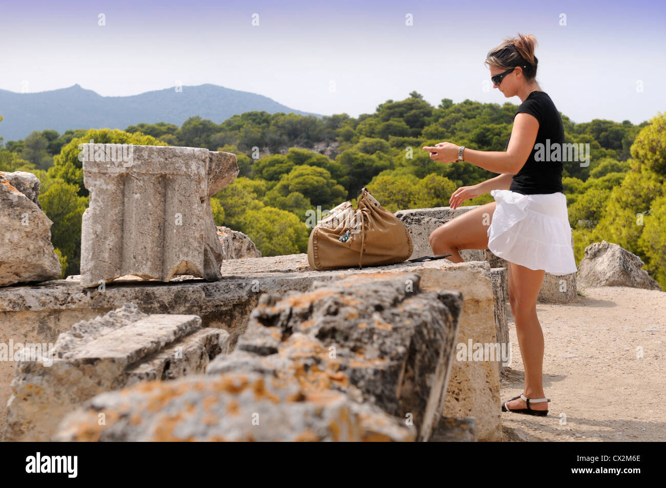 Un turista si applica il blocco sun durante un tour del Tempio di Aphaia o Afea sull'isola greca di Egina Foto Stock