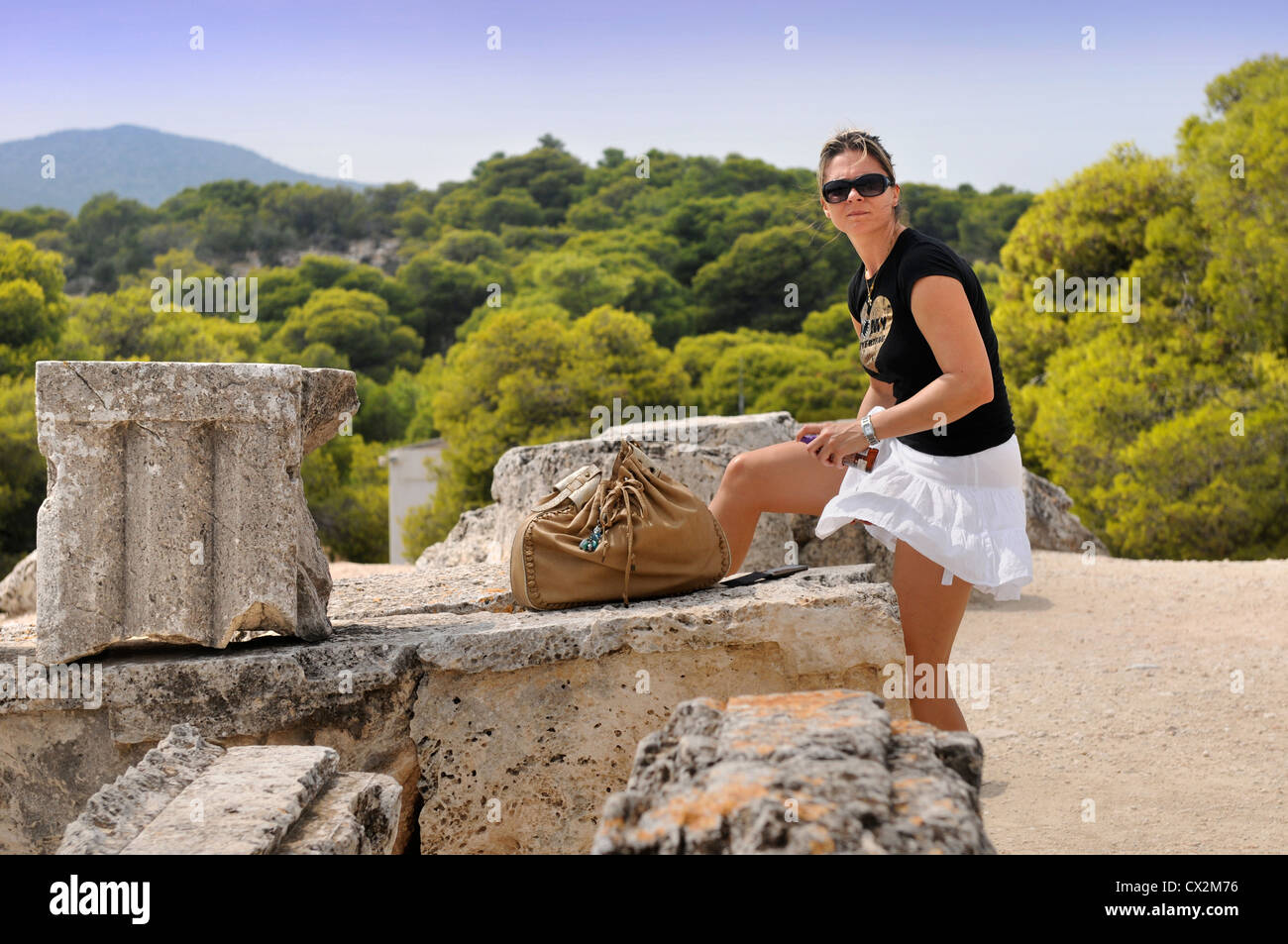 Un turista si applica il blocco sun durante un tour del Tempio di Aphaia o Afea sull'isola greca di Egina Foto Stock