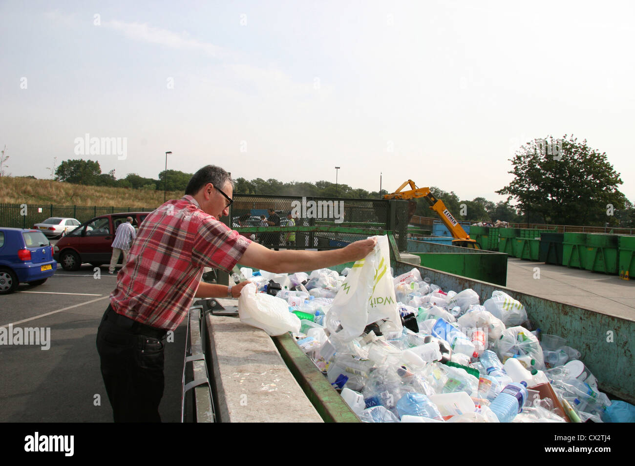 L'uomo gettando un sacco di elementi in plastica in un contenitore grande in un centro di riciclaggio a Barnet Hertfordshire, Regno Unito Foto Stock