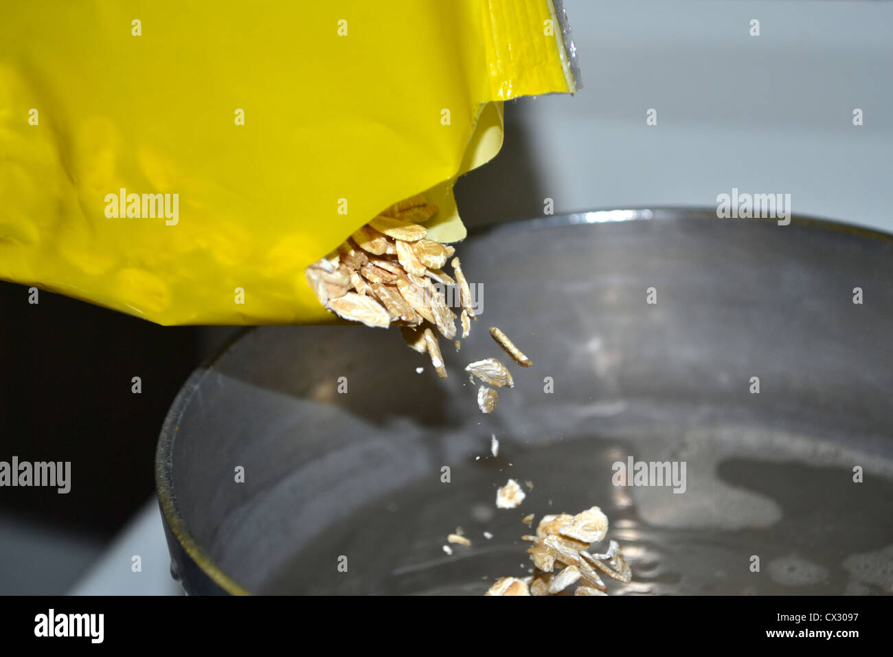 Versando l'avena in pentola di acqua Foto Stock