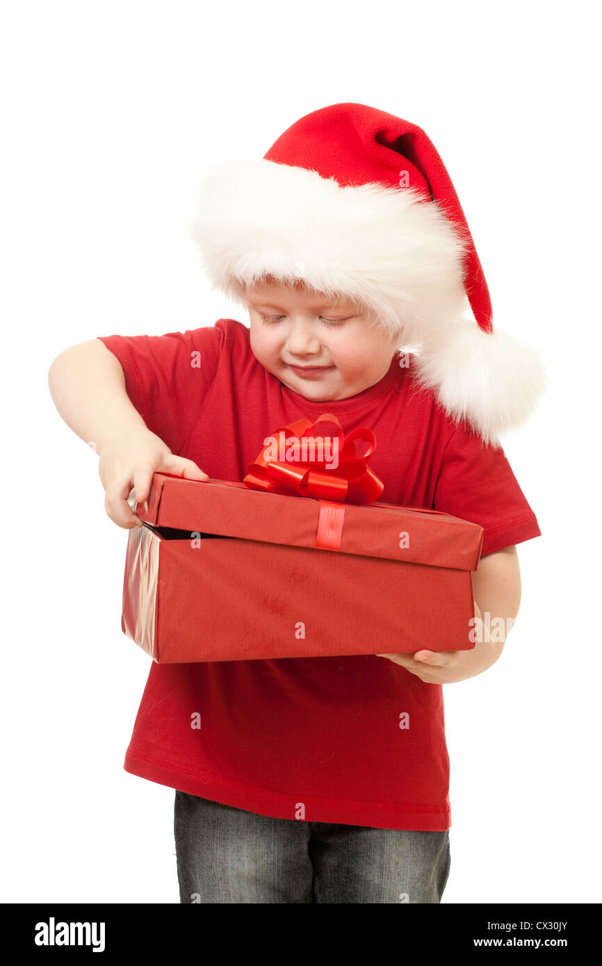 Adorable boy in Santa hat apertura regalo di Natale nel riquadro rosso isolato su bianco Foto Stock