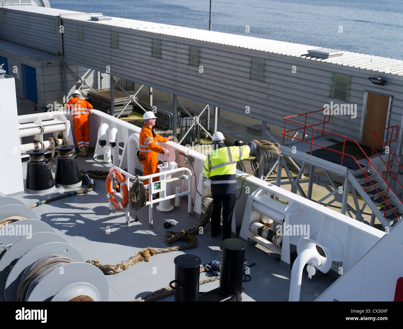 Dh Northlink ferries SHIPPING UK verricello operatore uomo e uomo di gettare la cima di ormeggio alla banchina Foto Stock