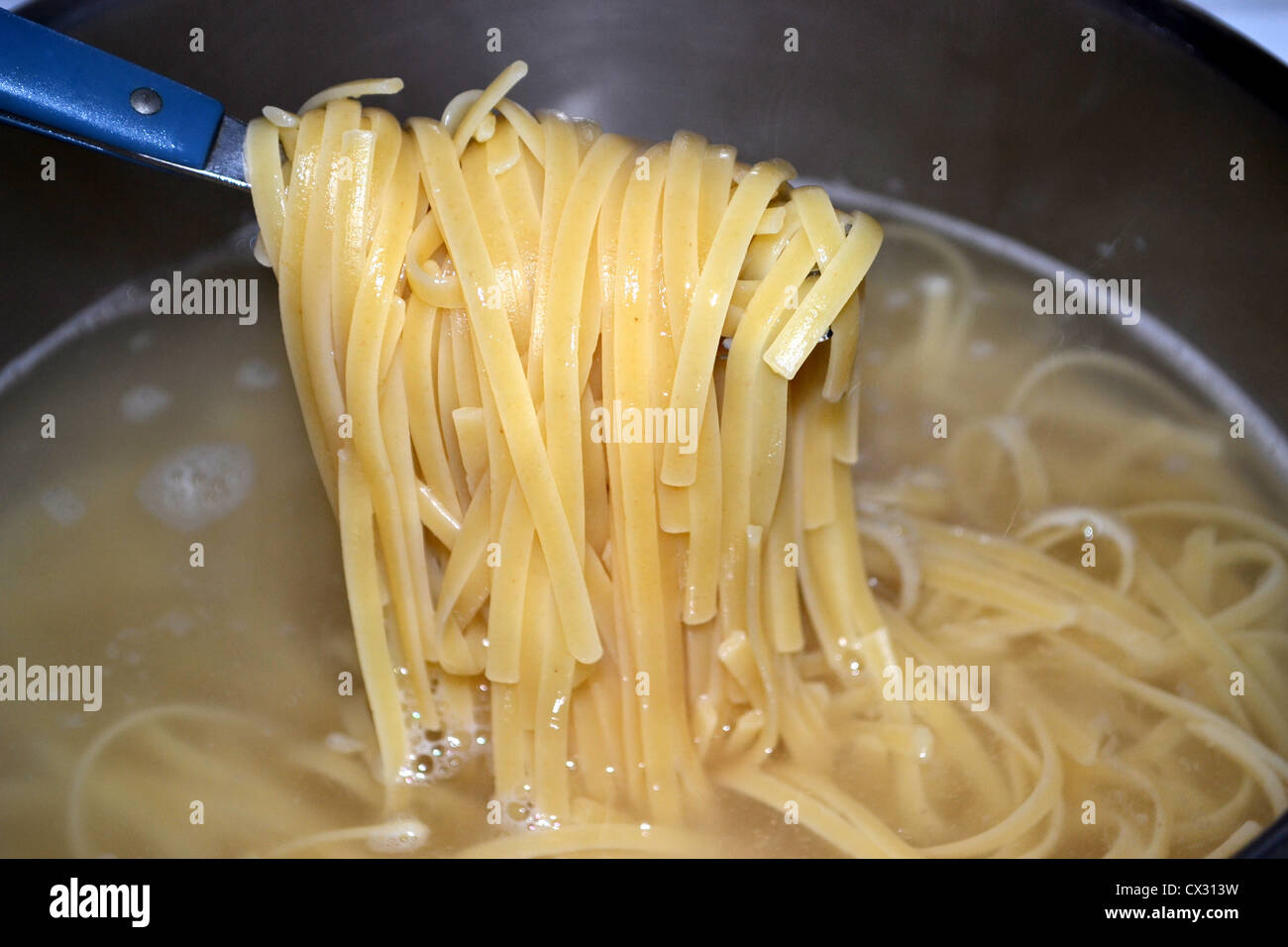 Linguine (anche "Linguini") è una forma di pasta - piatta come fettuccine e trenette. La cottura in pentola di acqua bollente Foto Stock