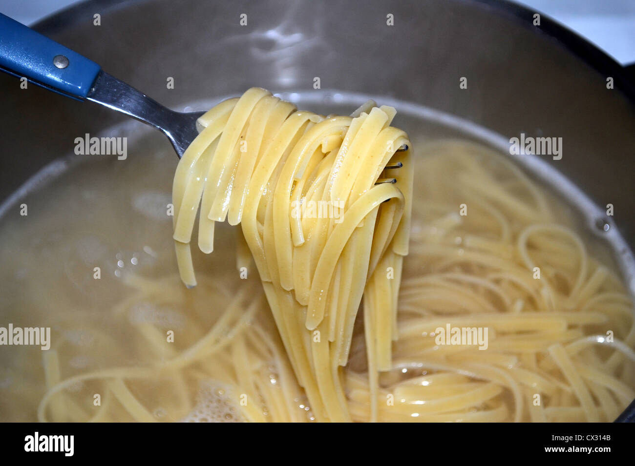 Linguine (anche "Linguini") è una forma di pasta - piatta come fettuccine e trenette. La cottura in pentola di acqua bollente Foto Stock